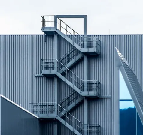 An exterior metal fire escape staircase on the facade of an industrial building