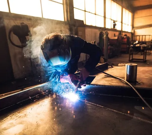 A welder in a protective mask welding a metal part in the workshop